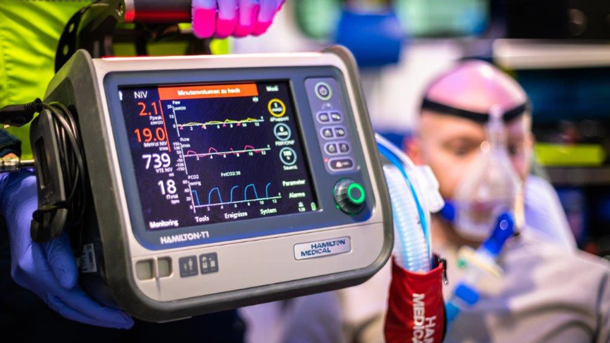 Un ambulancier utilise un appareil de ventilation pour surveiller un patient portant un masque à oxygène dans l'ambulance lors d'une intervention d'urgence.